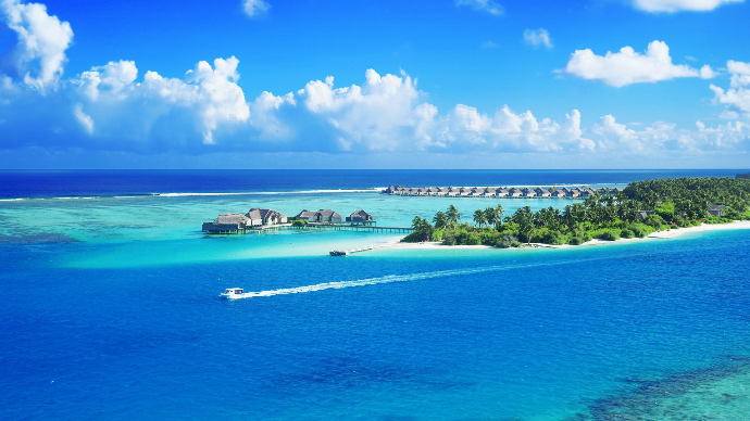 Des eaux cristallines entourent un luxueux complexe Maldives sous un ciel bleu brillant.