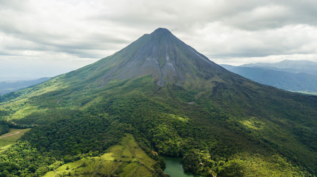 Vue aérienne dramatique du luxuriant volcan Arenal au Costa Rica contre un ciel nuageux.