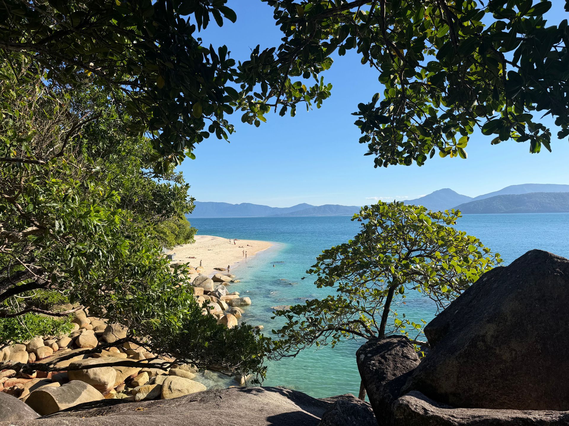 Scène de plage tropicale sereine avec des eaux turquoise et une végétation luxuriante, parfaite pour une escapade tranquille.
