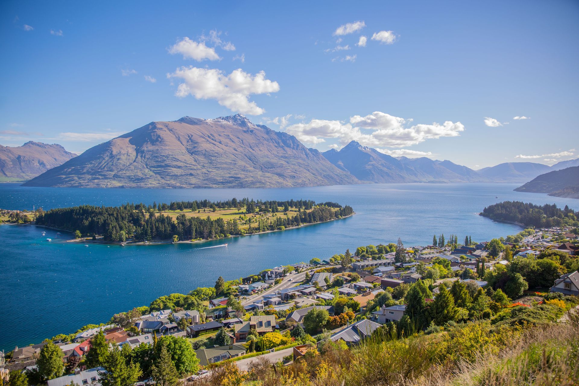 Vue aérienne à couper le souffle de Queenstown au bord du lac Wakatipu, entourée de montagnes majestueuses sous un ciel dégagé.  Plus d’infos  Partager