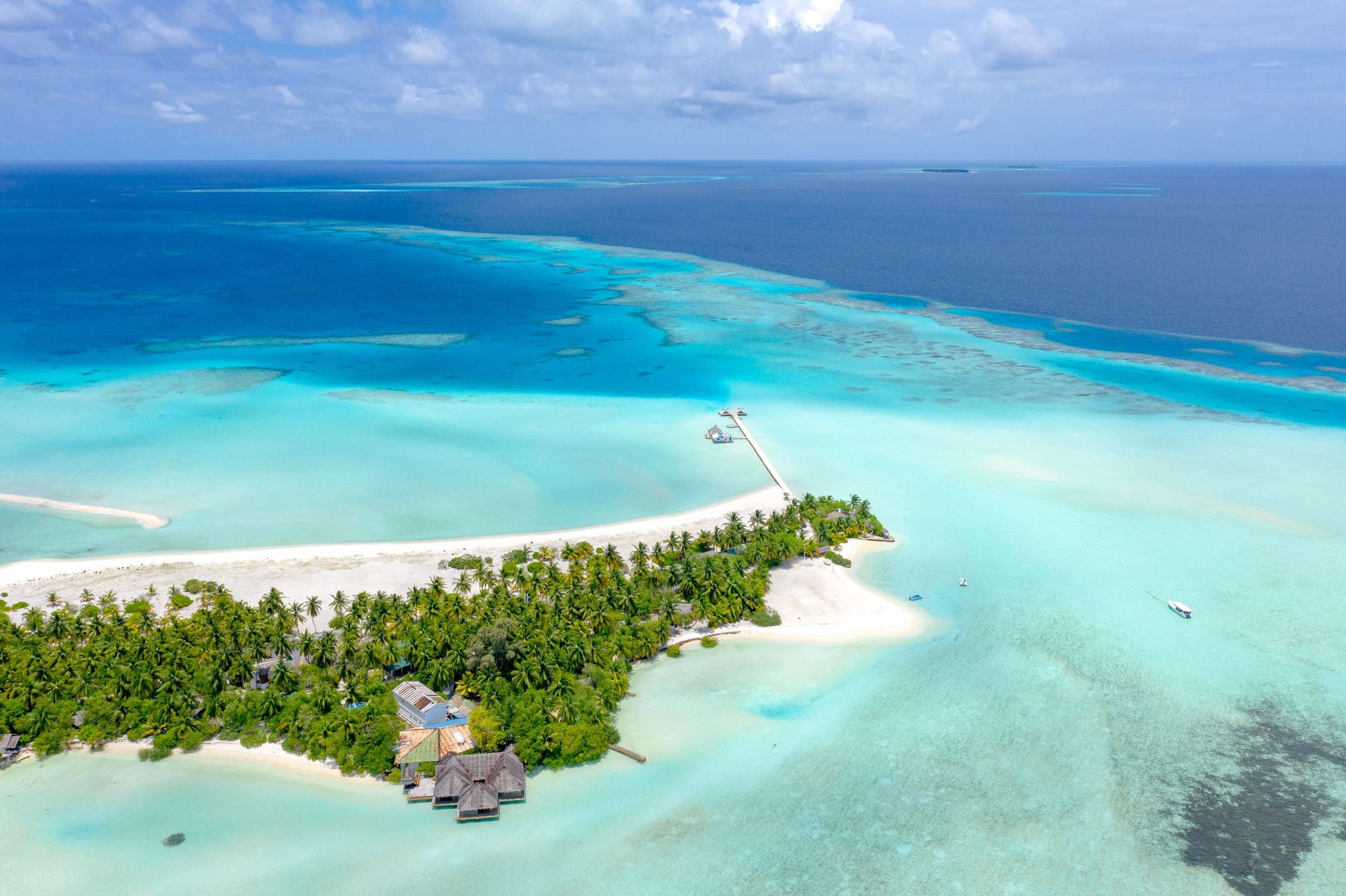 Vue aérienne d'une île tropicale avec des eaux turquoise et des plages de sable blanc aux Maldives.