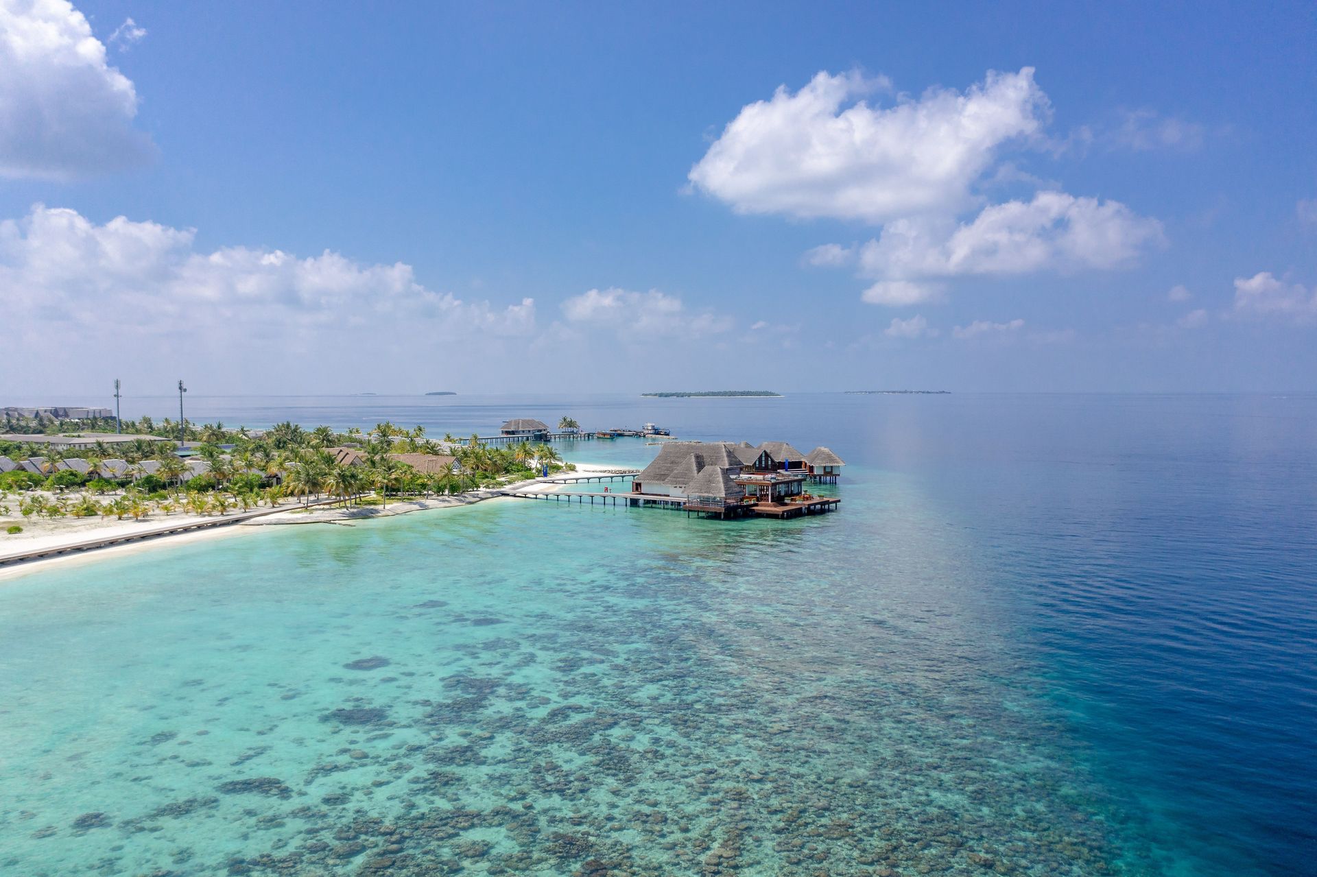 Vue aérienne pittoresque de l'île Meedhoo, Maldives, mettant en valeur des eaux turquoises et des bungalows sur pilotis.