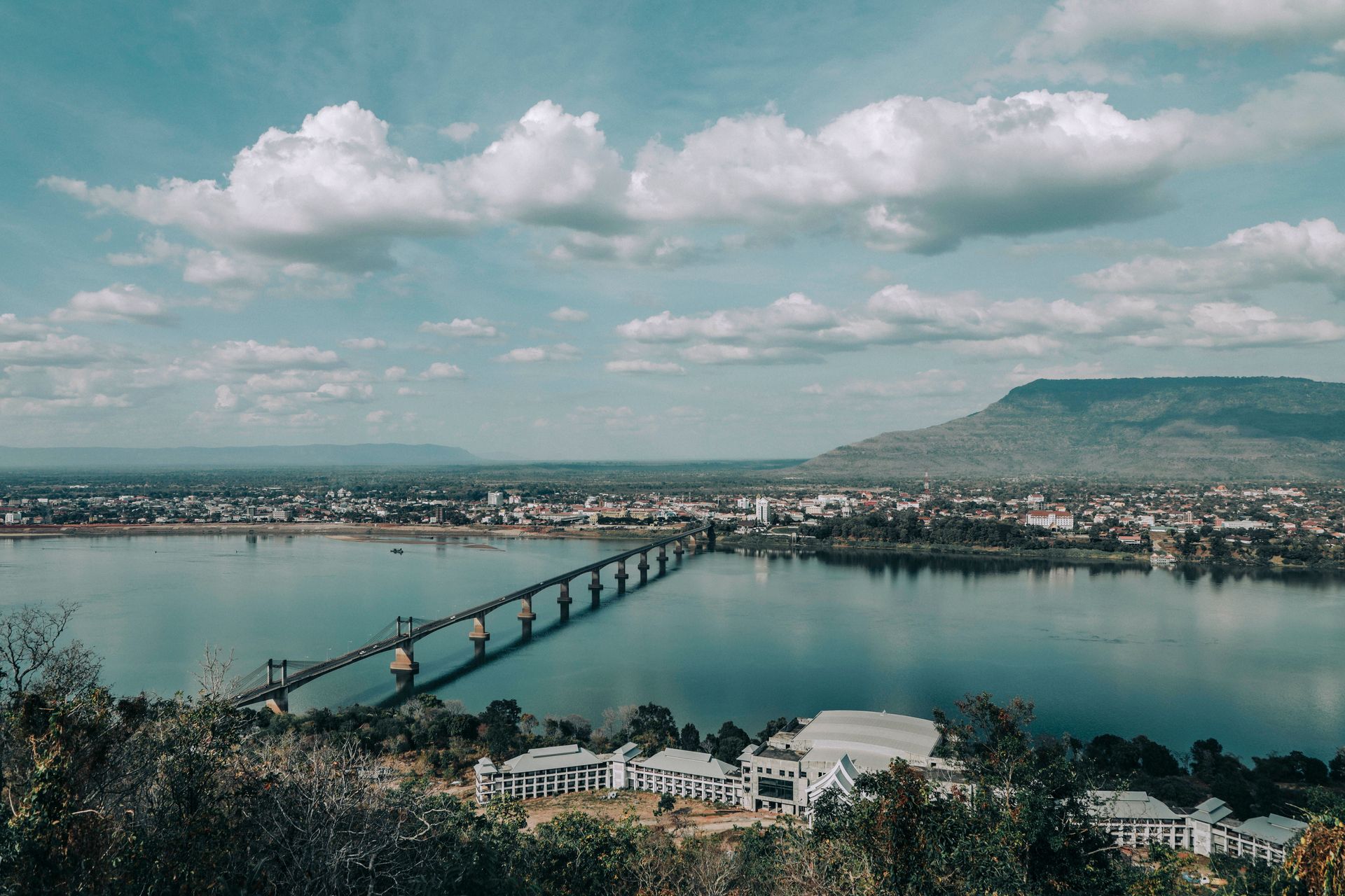 Un pont pittoresque traverse le fleuve Mékong dans un paysage laotien tranquille.