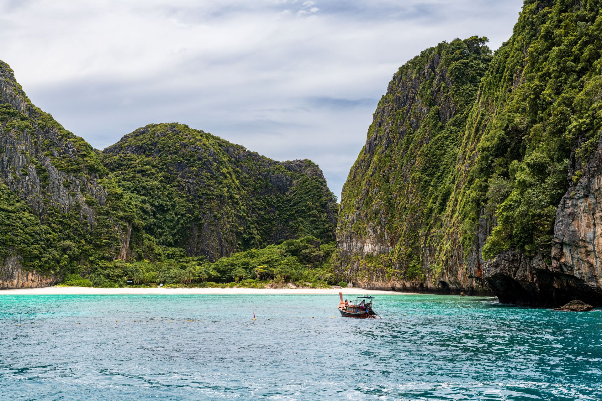 Vue idyllique d'un bateau traditionnel contre des falaises de calcaire et des eaux turquoise à Phuket, Thaïlande.