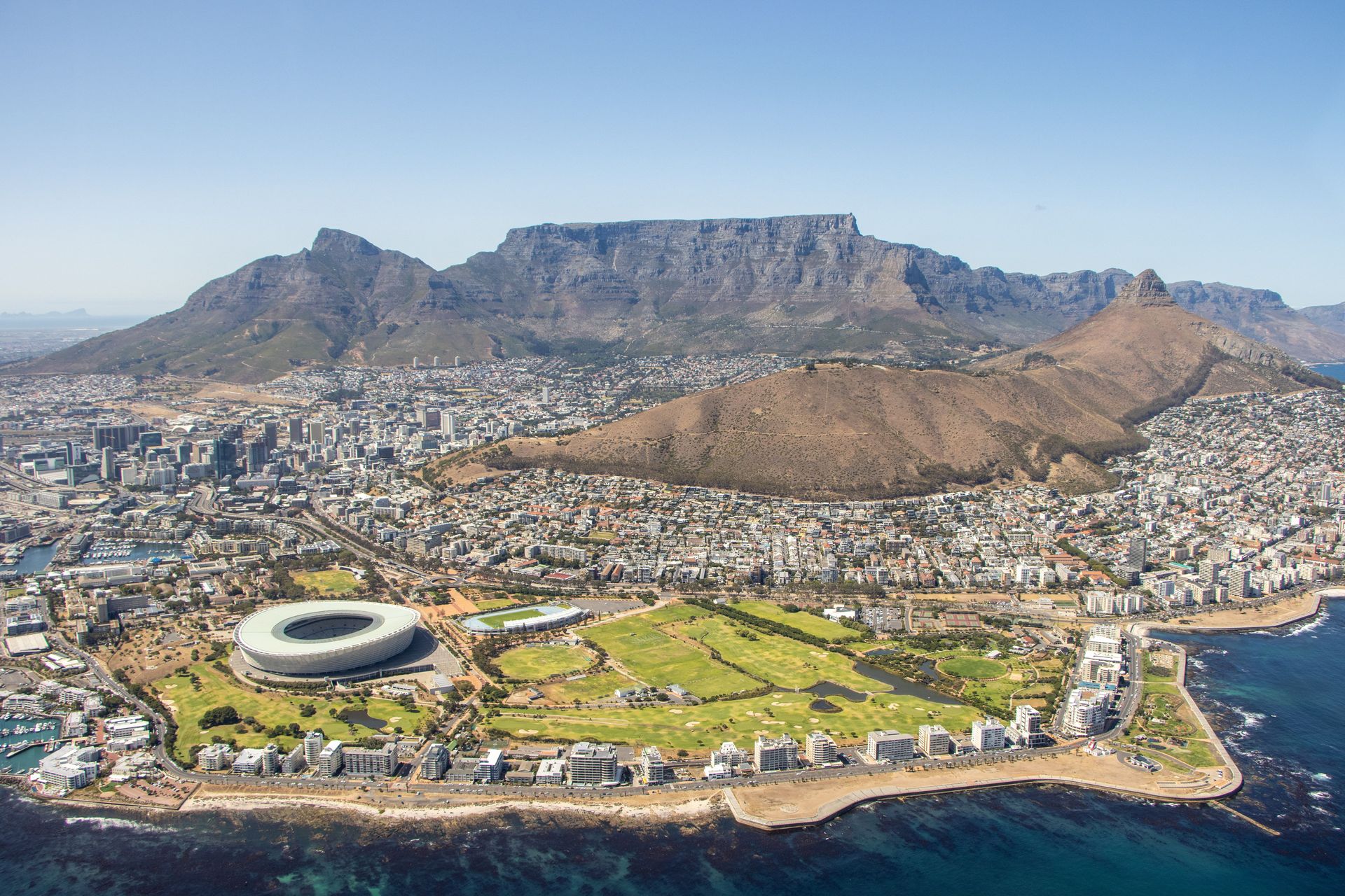 Une vue aérienne à couper le souffle de Cape Town, mettant en valeur la Montagne de la Table, le paysage urbain et le stade au bord de la mer.
