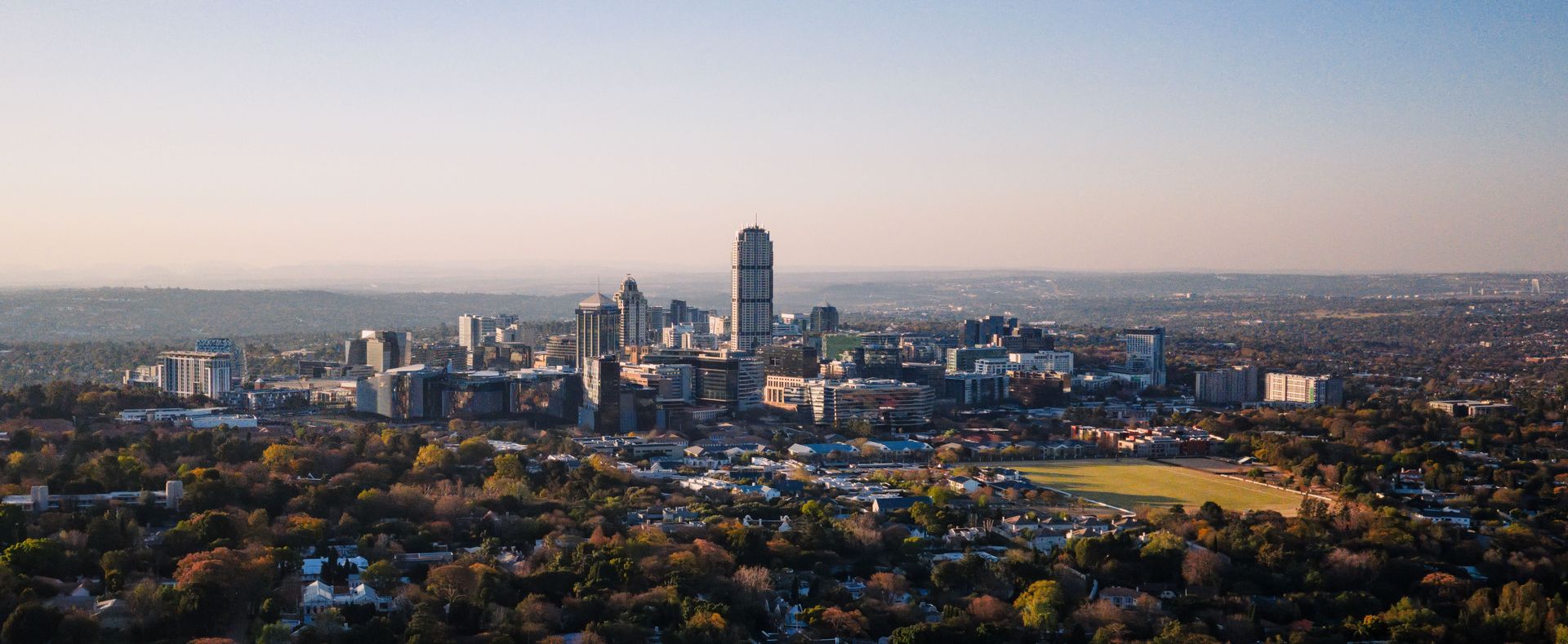 Superbe vue aérienne de Sandton, Gauteng, présentant l'horizon urbain et l'aménagement suburbain sous un ciel clair.