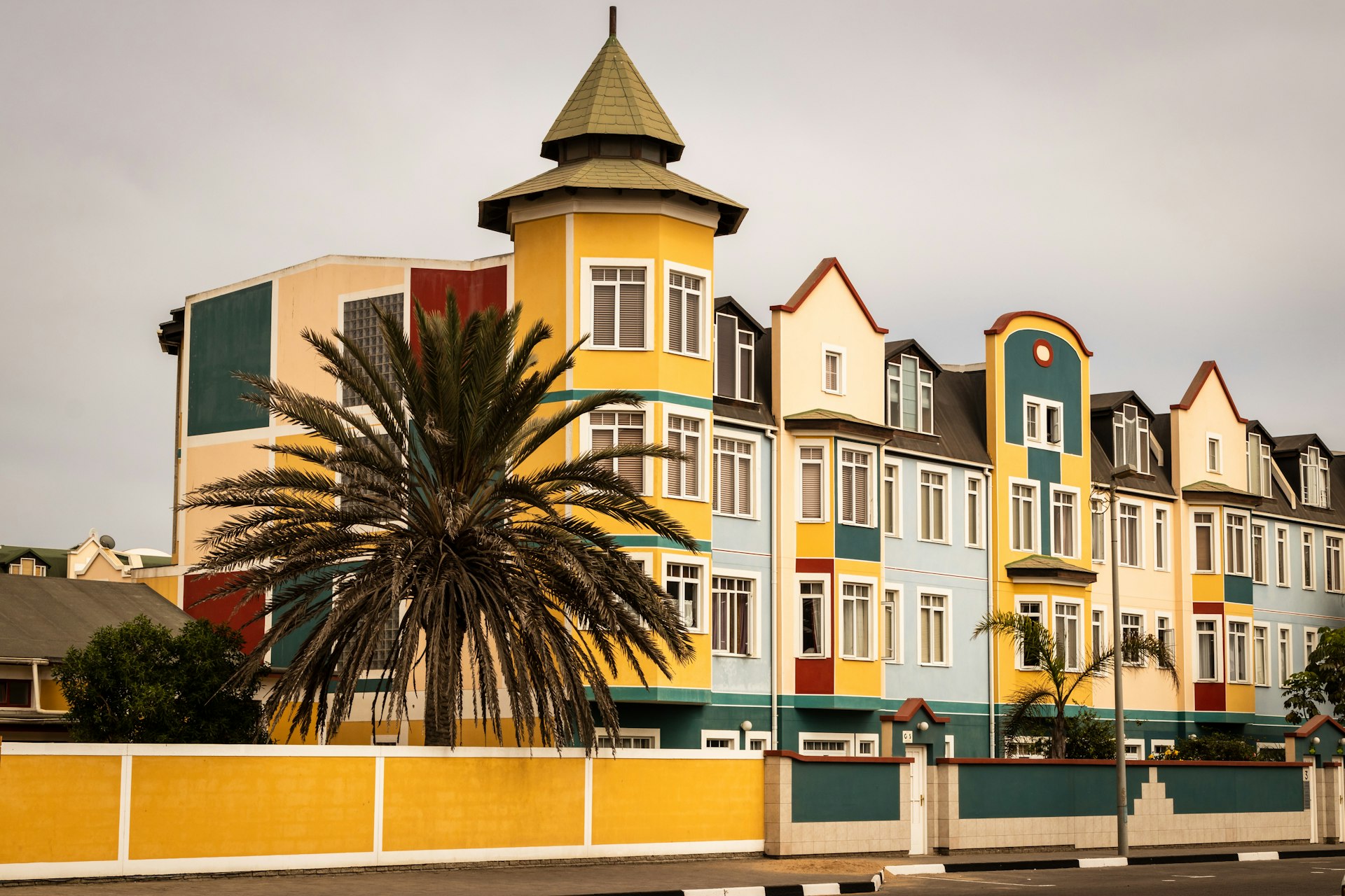 Bâtiment blanc et jaune dans la ville de Swakopmund avec un palmier en premier plan