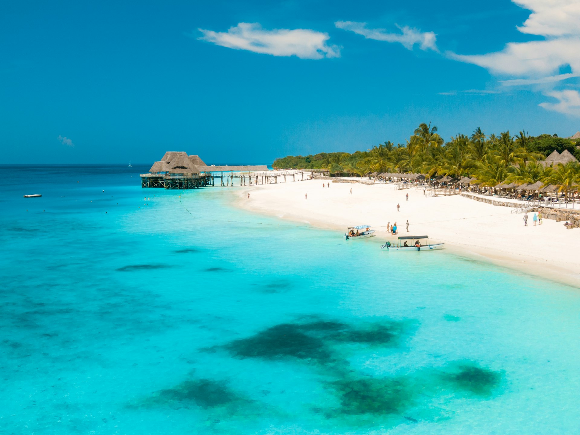 Une plage de sable blanc bordée de palmiers, avec une jetée en bois à Zanzibar, en Tanzanie.