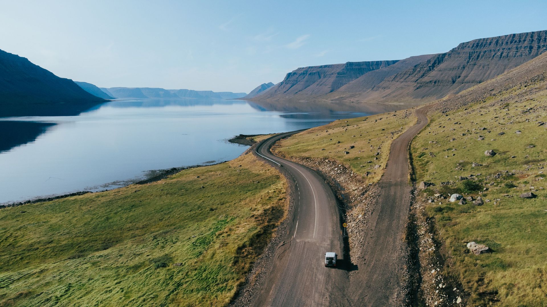 Une vue aérienne époustouflante d'une route sinueuse le long des fjords dans la région des Westfjords en Islande, parfaite pour les amateurs de voyage.