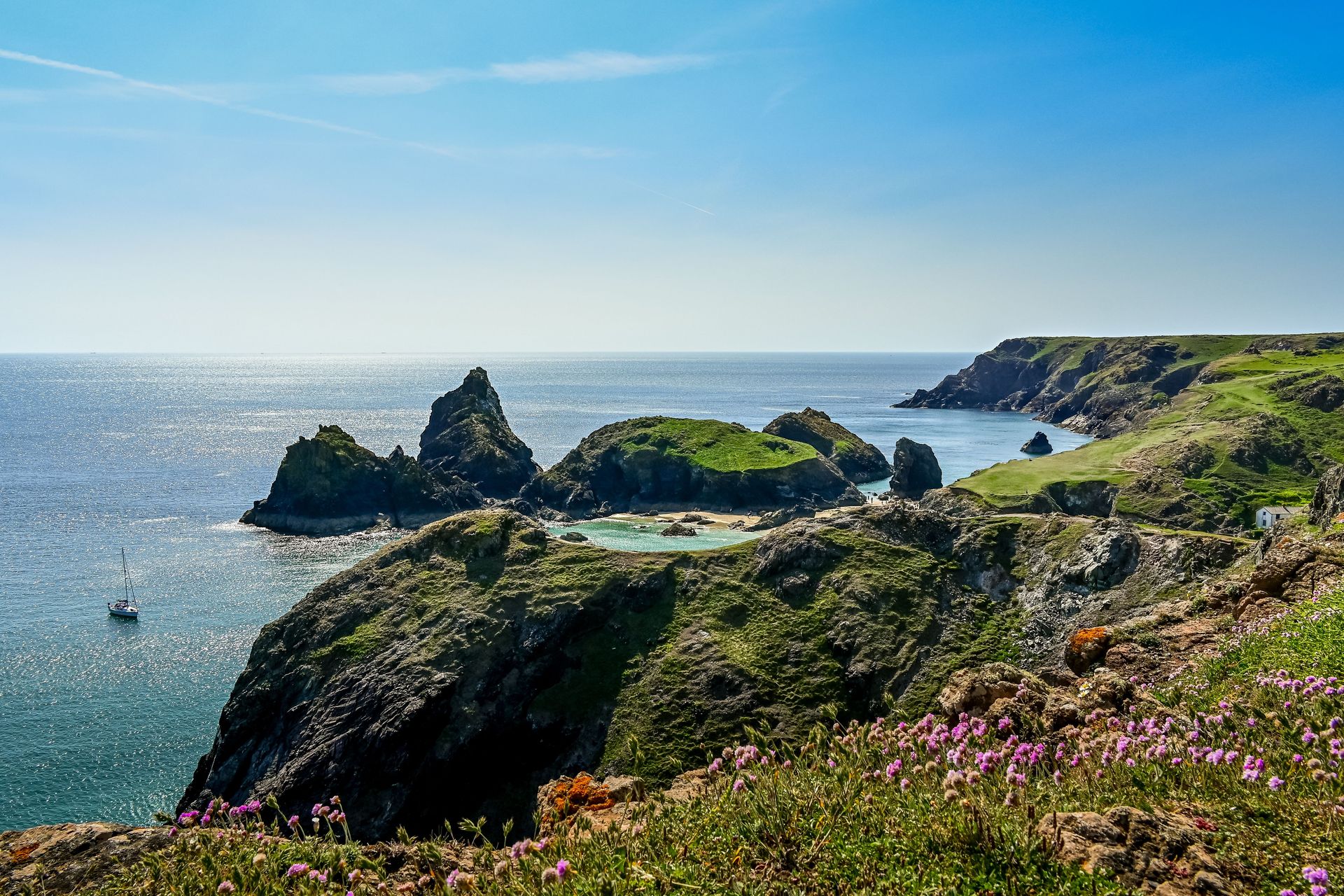 Explorez le magnifique paysage côtier de Kynance Cove, en Cornouailles, avec sa verdure vibrante et ses falaises rocheuses.