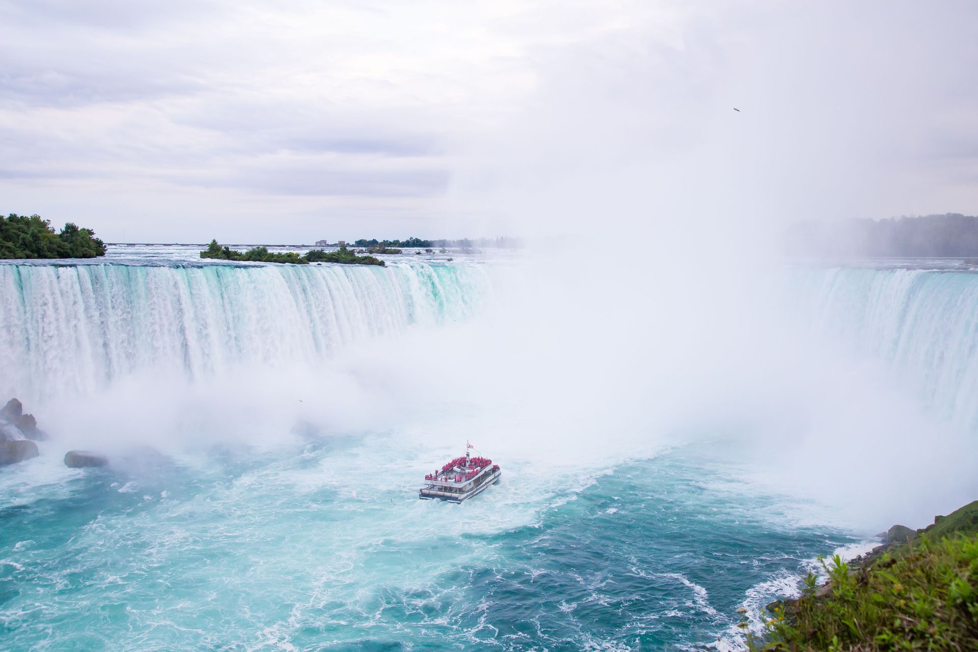 Une vue pittoresque des Chutes du Niagara avec un bateau de tourisme naviguant dans les eaux embrumées.