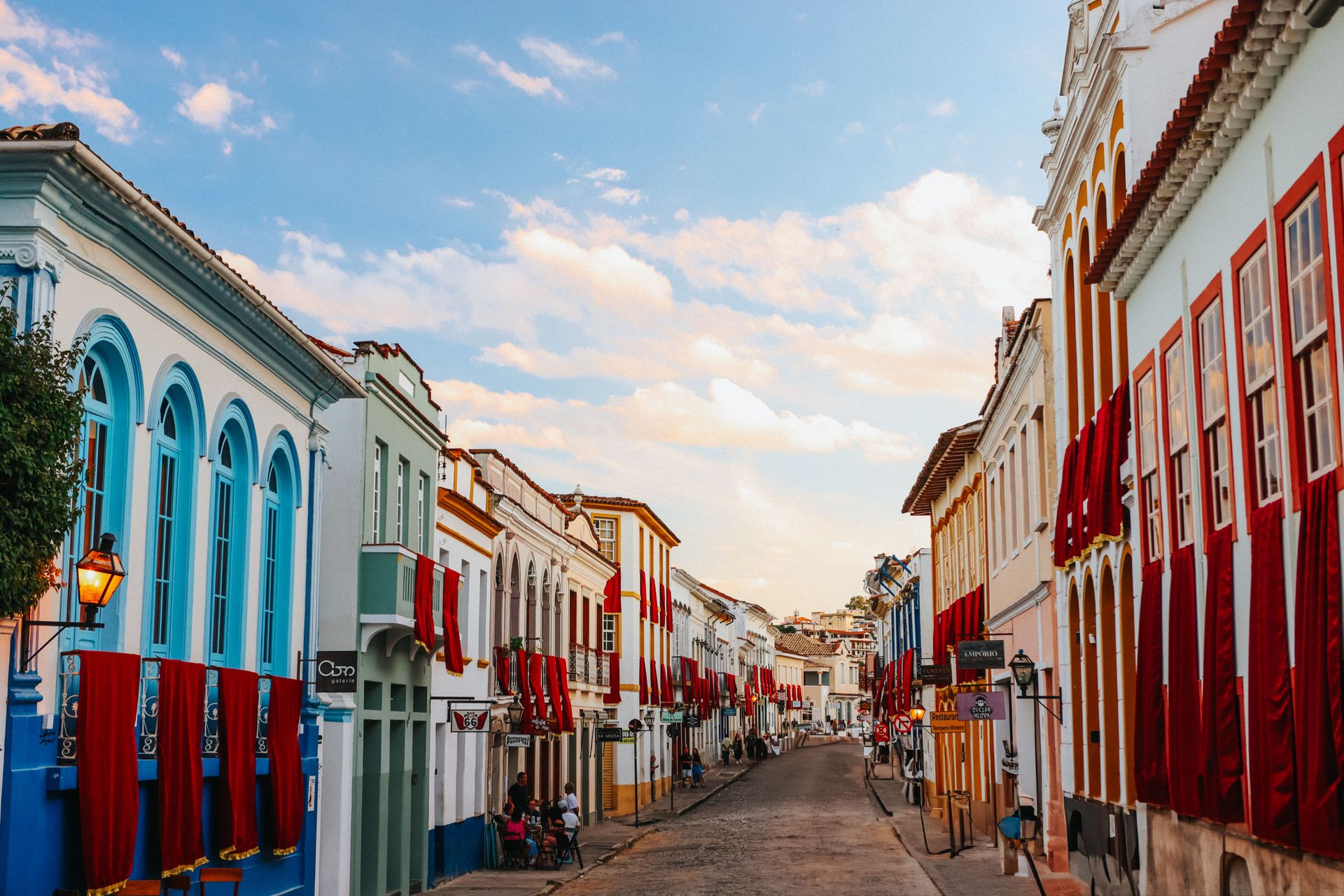 Rue coloniale vibrante avec des façades colorées et des décorations rouges au coucher du soleil.