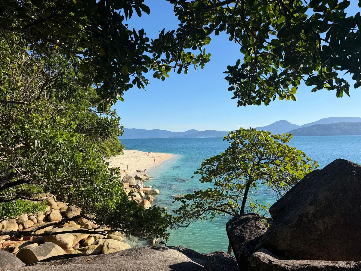 Scène de plage tropicale sereine avec des eaux turquoise et une végétation luxuriante, parfaite pour une escapade tranquille.