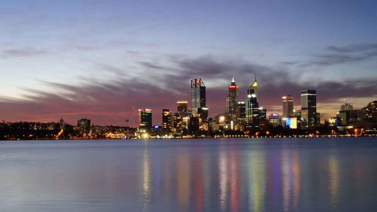 Une vue à couper le souffle de la skyline illuminée de Perth se reflétant sur l'eau calme au crépuscule.