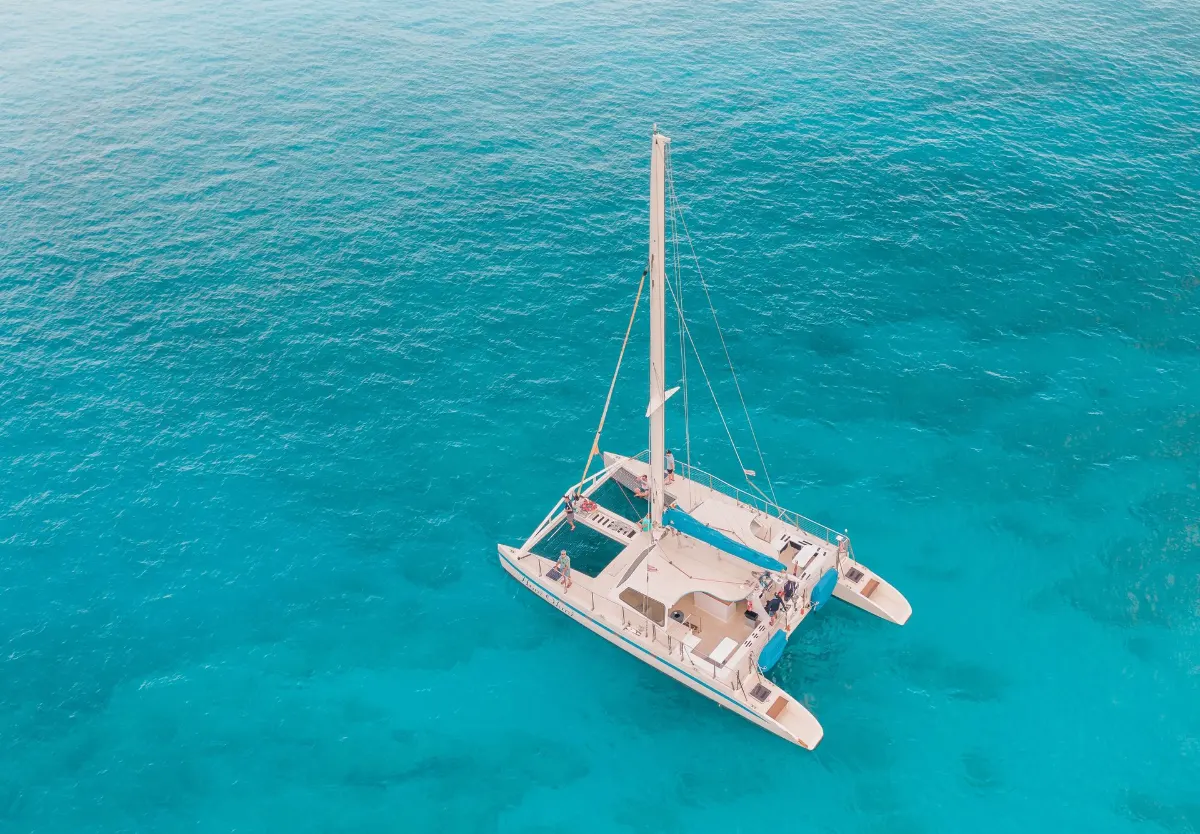 Superbe vue aérienne d'un catamaran naviguant dans des eaux turquoises cristallines.