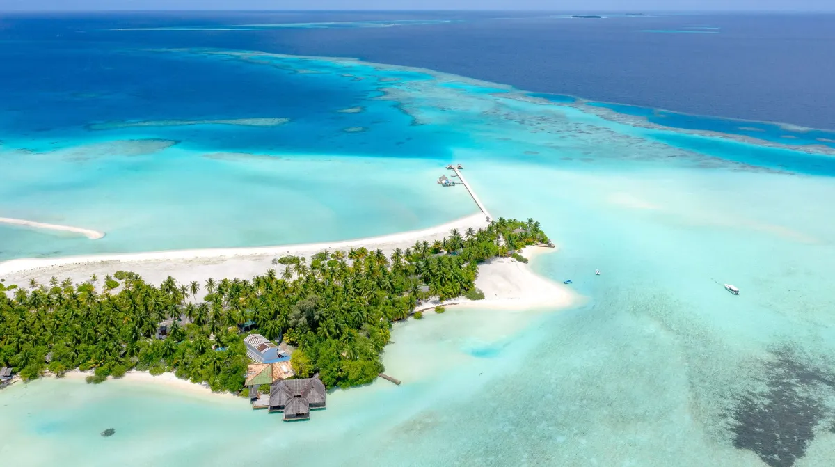 Vue aérienne d'une île tropicale avec des eaux turquoise et des plages de sable blanc aux Maldives.