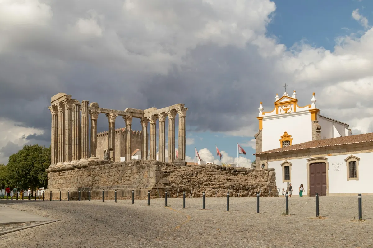 Le Temple romain d'Évora, colonnes corinthiennes en ruine sous un ciel orageux, face à la Pousada dos Lóios.