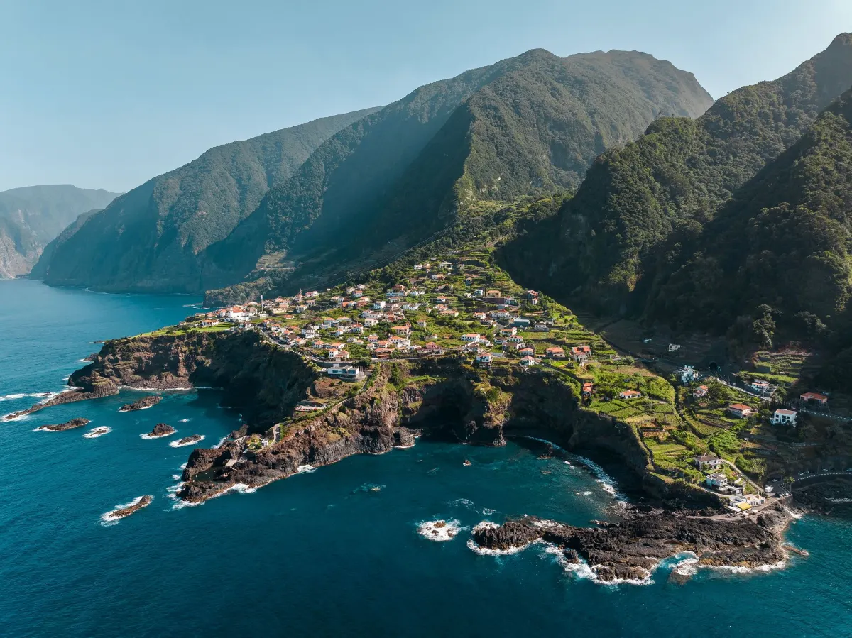 Vue aérienne pittoresque d'un village côtier à Madère, Portugal, avec des paysages verdoyants et des côtes rocheuses.