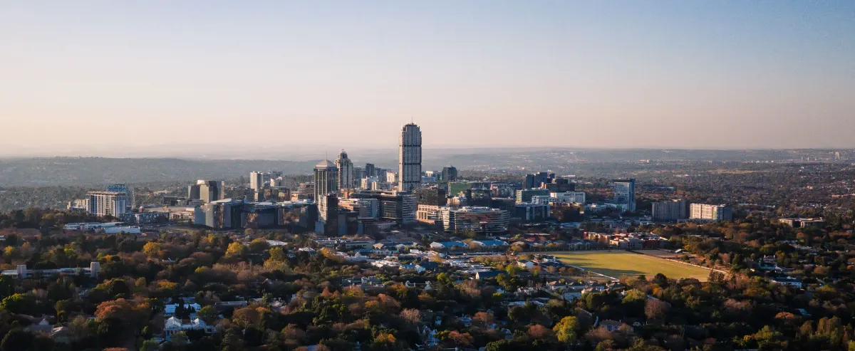 Superbe vue aérienne de Sandton, Gauteng, présentant l'horizon urbain et l'aménagement suburbain sous un ciel clair.