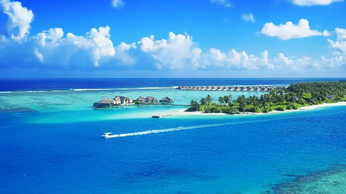 Des eaux cristallines entourent un luxueux complexe Maldives sous un ciel bleu brillant.