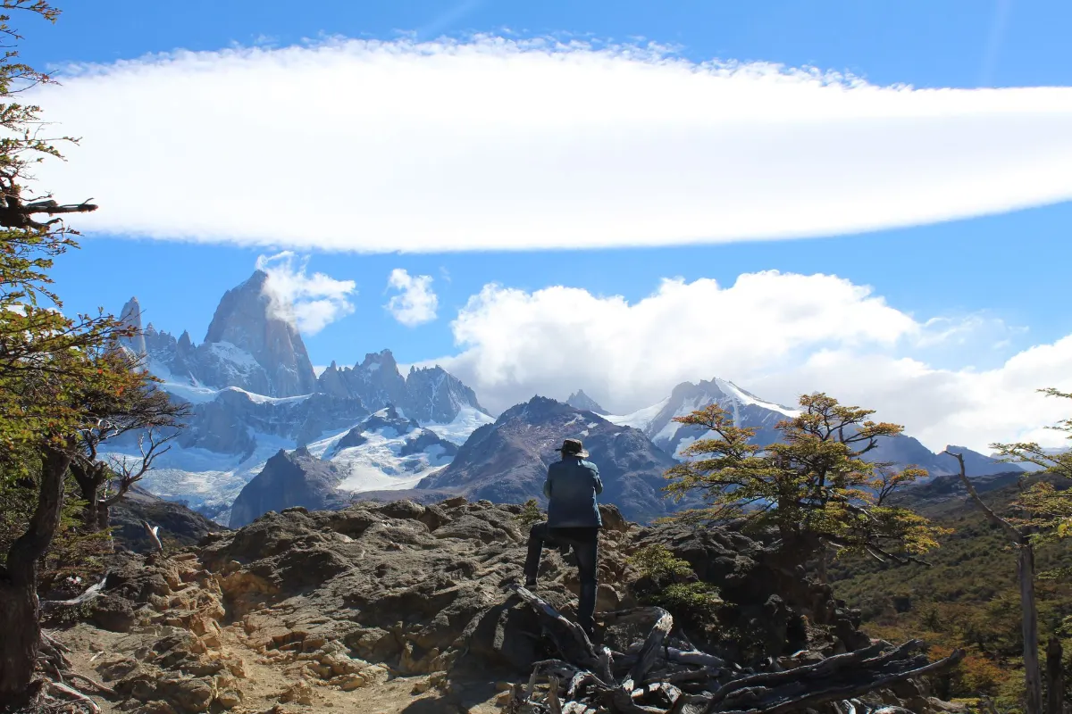 Un randonneur solitaire admire la vue imprenable sur le mont Fitz Roy en Patagonie, sous un ciel d'un bleu limpide.
