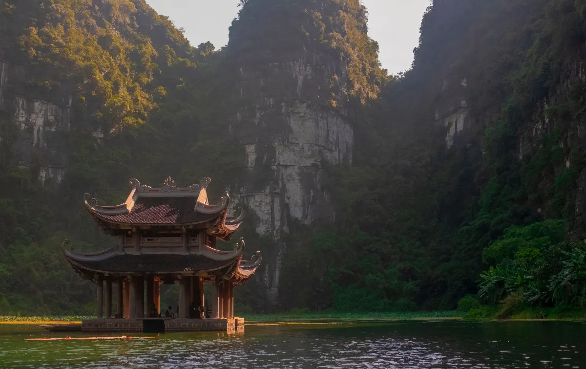 Une pagode tranquille sur un lac entouré de montagnes luxuriantes à Ninh Bình, Vietnam.