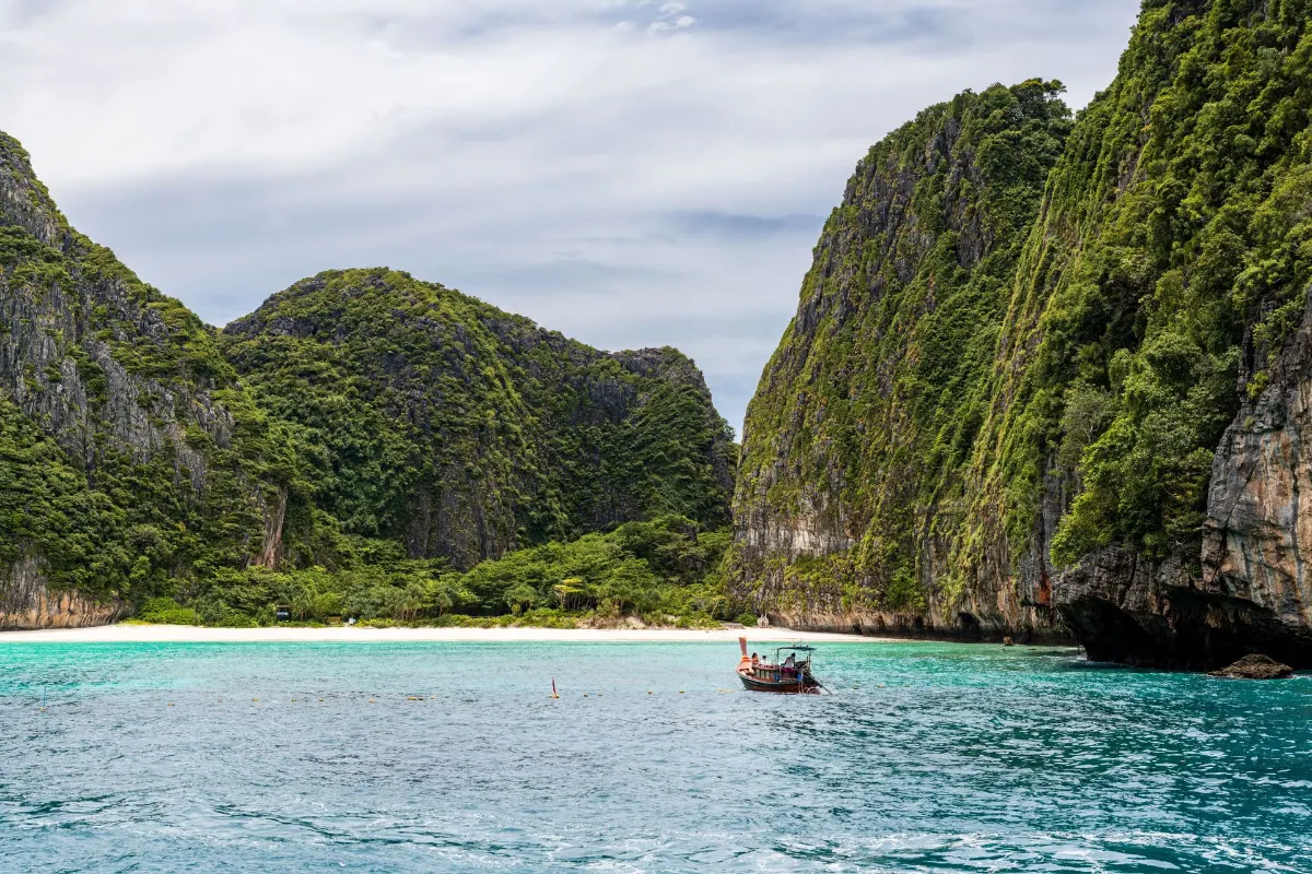 Vue idyllique d'un bateau traditionnel contre des falaises de calcaire et des eaux turquoise à Phuket, Thaïlande.