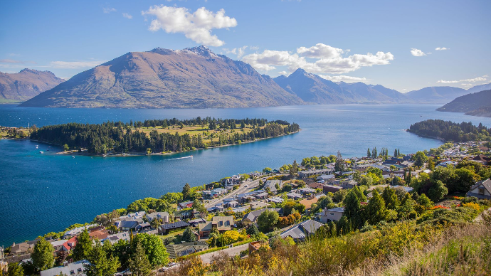 Vue aérienne à couper le souffle de Queenstown au bord du lac Wakatipu, entourée de montagnes majestueuses sous un ciel dégagé.  Plus d’infos  Partager